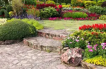 Jardin bien entretenu avec pelouse taillée, fleurs colorées et marches en pierre – Illustration des avis clients de Viedom Services.